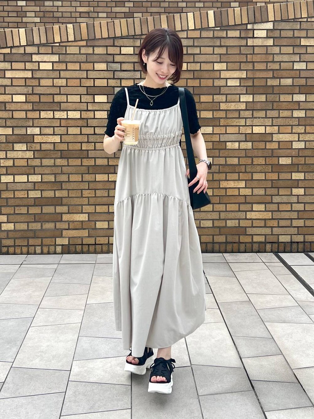 ブラック系のサンダル、ブラック系のTシャツ/カットソー、ブラック系のショルダーバッグを着用したレディースの夏コーディネートの2枚目の写真