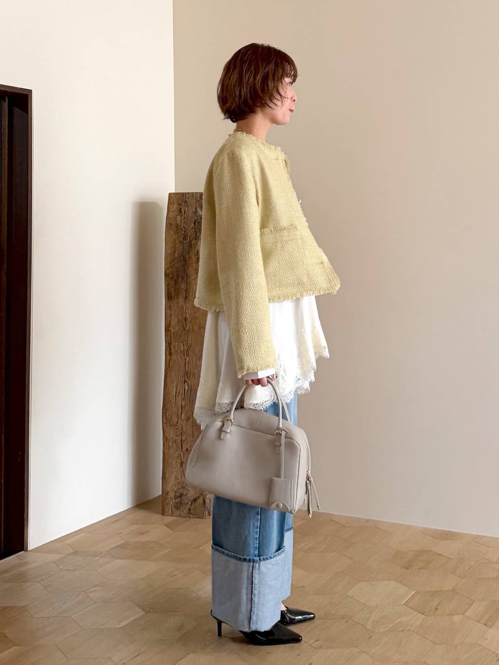ベージュ系のハンドバッグ、ホワイト系のキャミソール、イエロー系のノーカラージャケットを着用したレディースの冬コーディネートの2枚目の写真