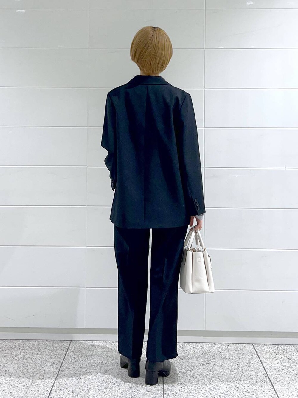 グレー系のTシャツ/カットソー、ブラック系のブーツ、ホワイト系のショルダーバッグを着用したレディースの冬コーディネートの3枚目の写真