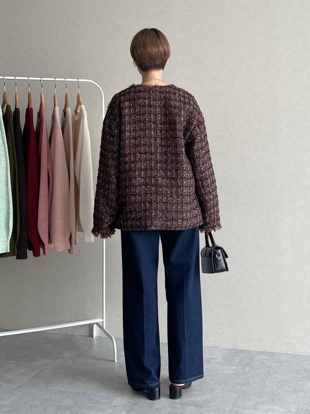 ブラウン系のノーカラージャケット、ブルー系のデニムパンツ、オレンジ系のニット/セーターを着用したレディースの秋コーディネートの3枚目の写真