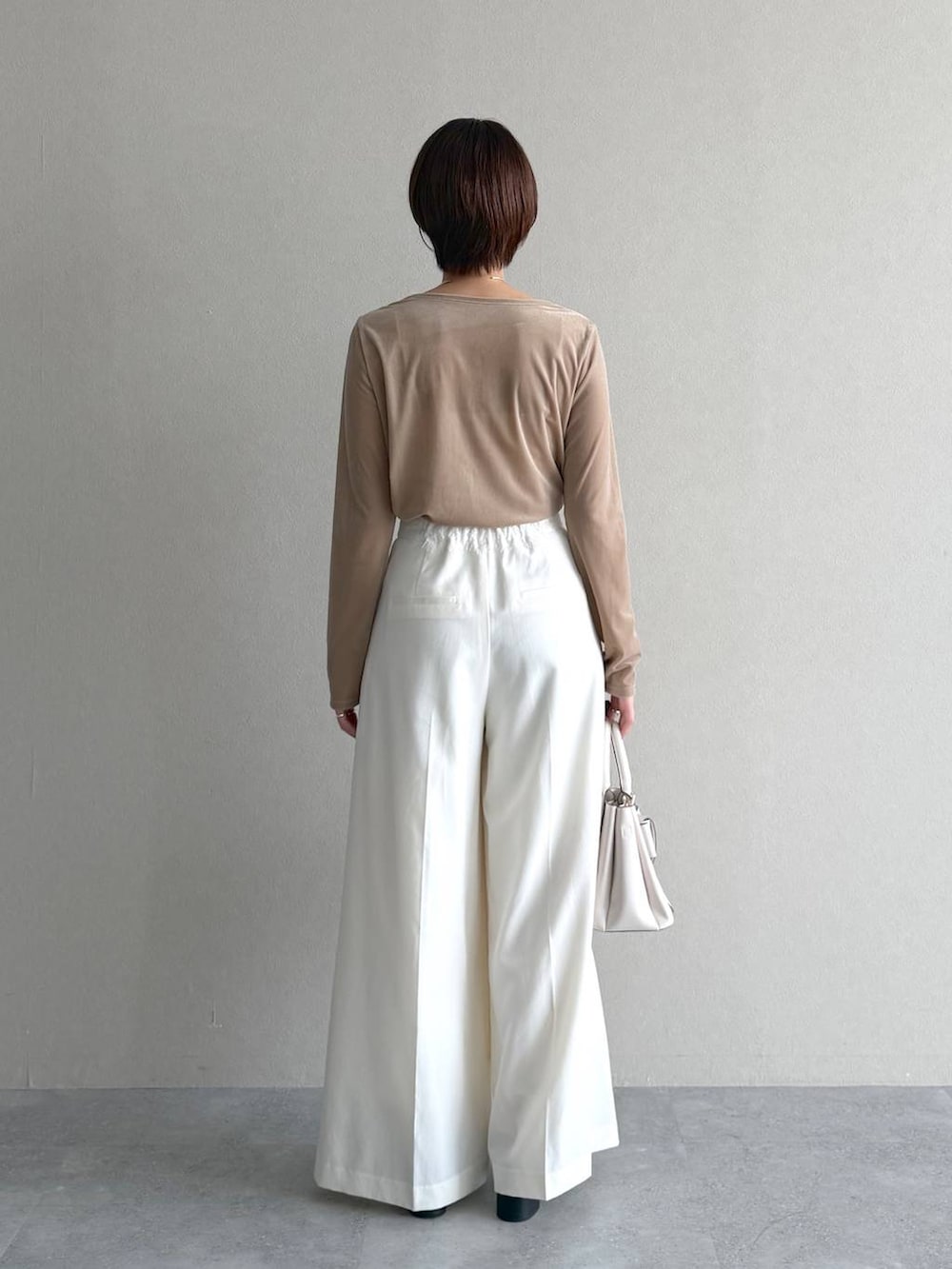 ベージュ系のトレンチコート、ベージュ系のTシャツ/カットソー、ホワイト系のスラックスを着用したレディースの秋コーディネートの7枚目の写真