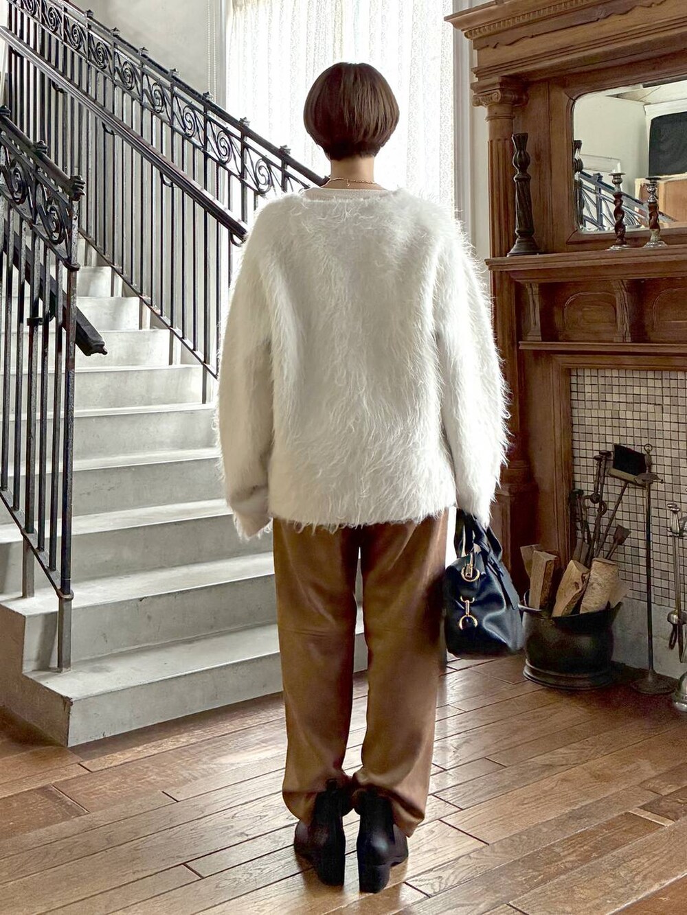 ブラック系のボストンバッグ、ブラウン系のスラックス、ホワイト系のニット/セーターを着用したレディースの秋コーディネートの3枚目の写真