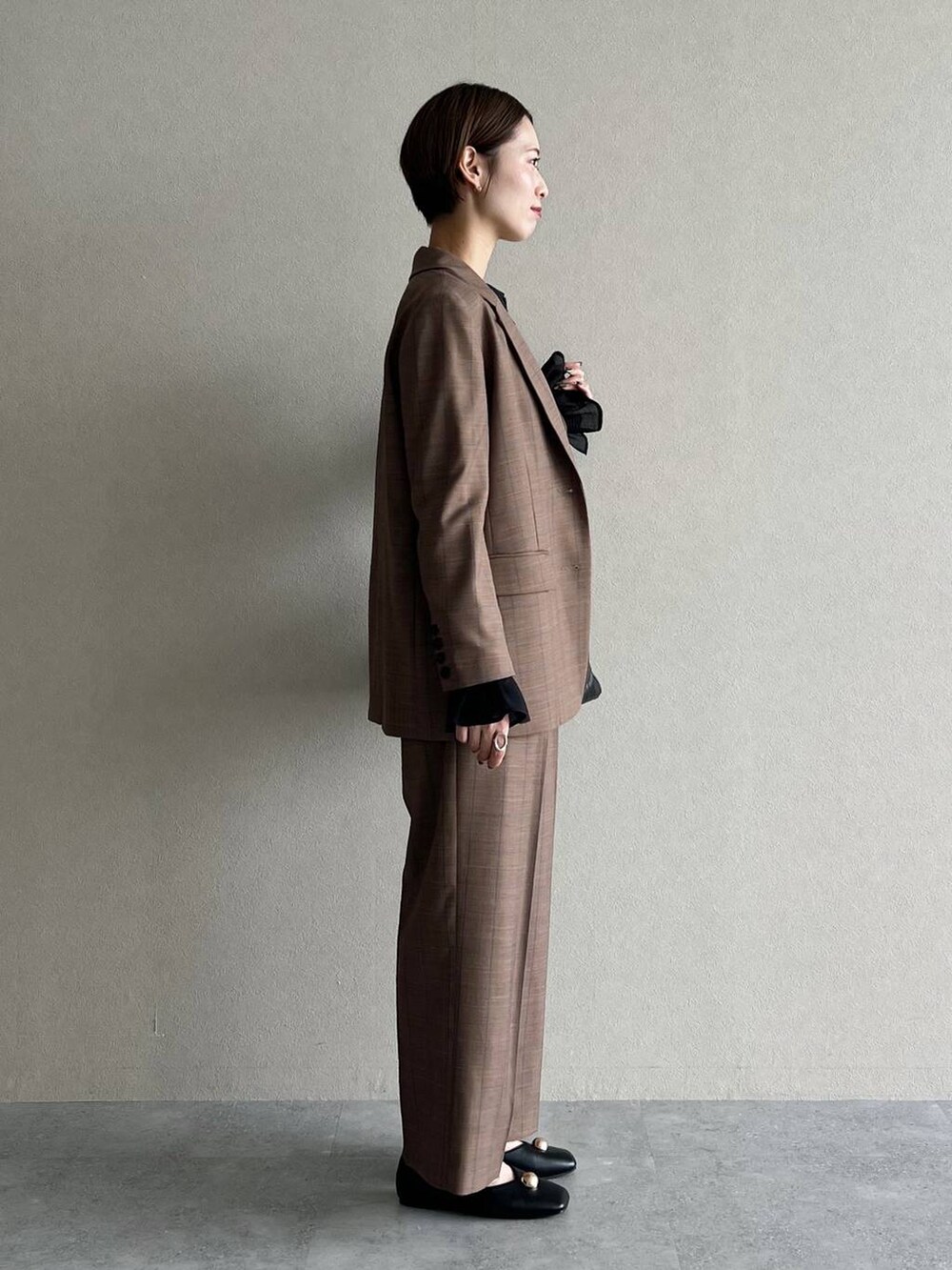 ベージュ系のスラックス、ベージュ系のテーラードジャケット、ブラック系のシャツ/ブラウスを着用したレディースの秋コーディネートの2枚目の写真