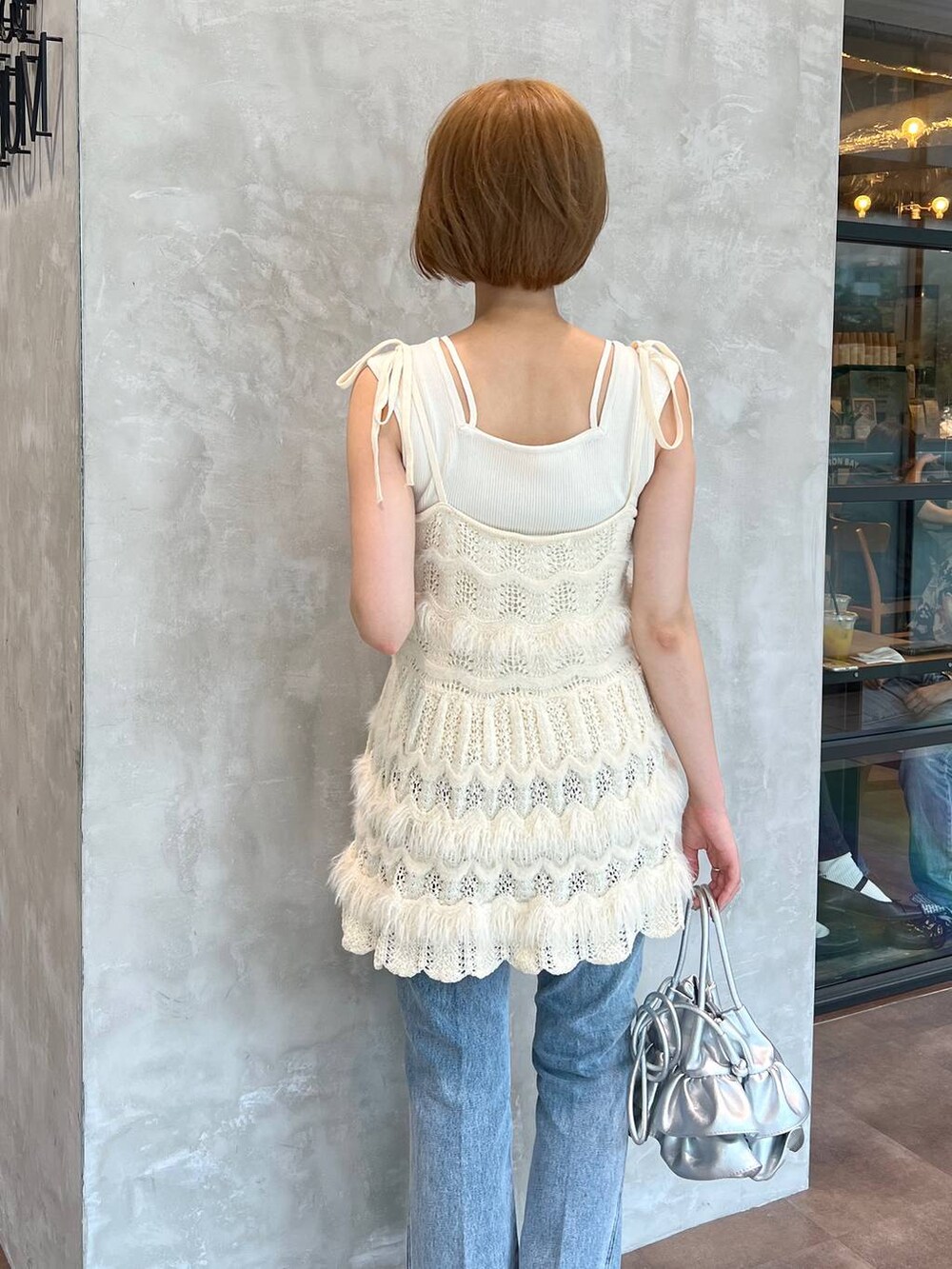 ブルー系のデニムパンツ、ホワイト系のキャミソール、ホワイト系のニット/セーターを着用したレディースの秋コーディネートの5枚目の写真