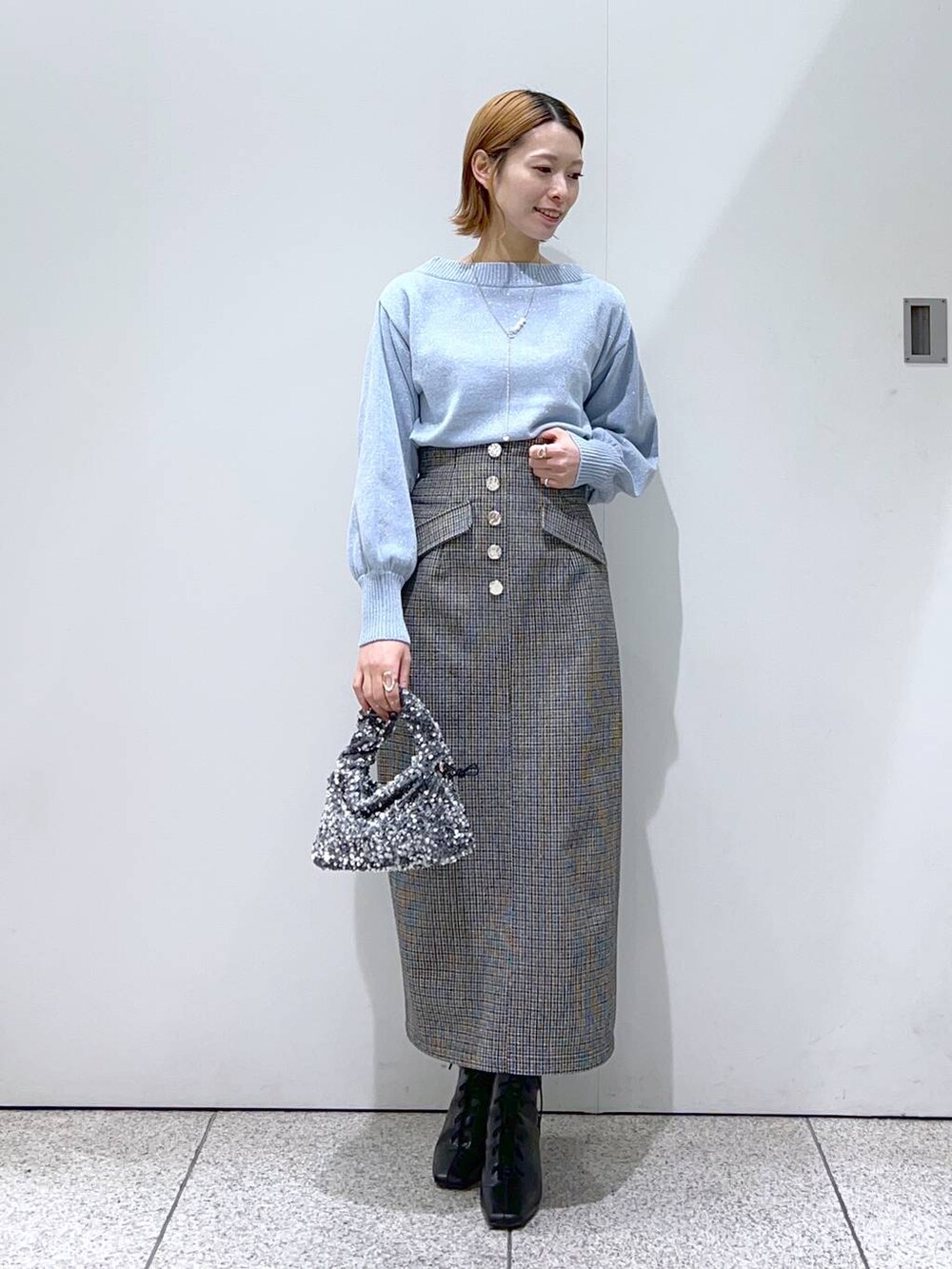 ブルー系のニット/セーター、ホワイト系のノーカラーコート、ブラック系のブーツを着用したレディースの冬コーディネートの4枚目の写真