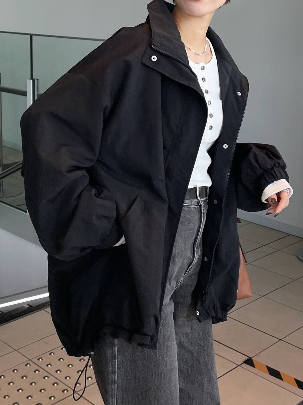 ブラウン系のボストンバッグ、ホワイト系のTシャツ/カットソー、ブラック系のブルゾンを着用したレディースの秋コーディネートの4枚目の写真