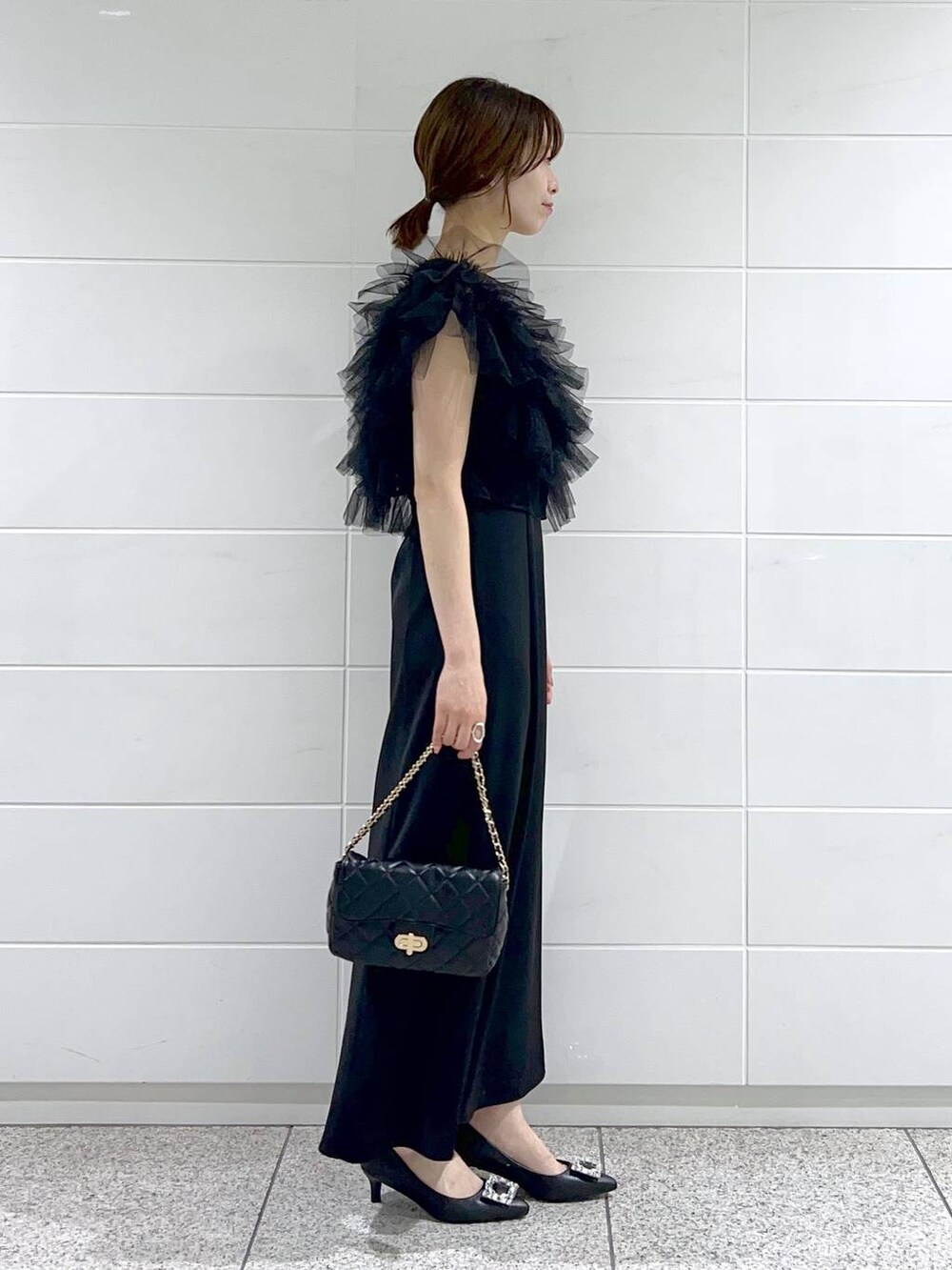 ブラック系のパンプス、ブラック系のドレス、ブラック系のショルダーバッグを着用したレディースの夏コーディネートの2枚目の写真