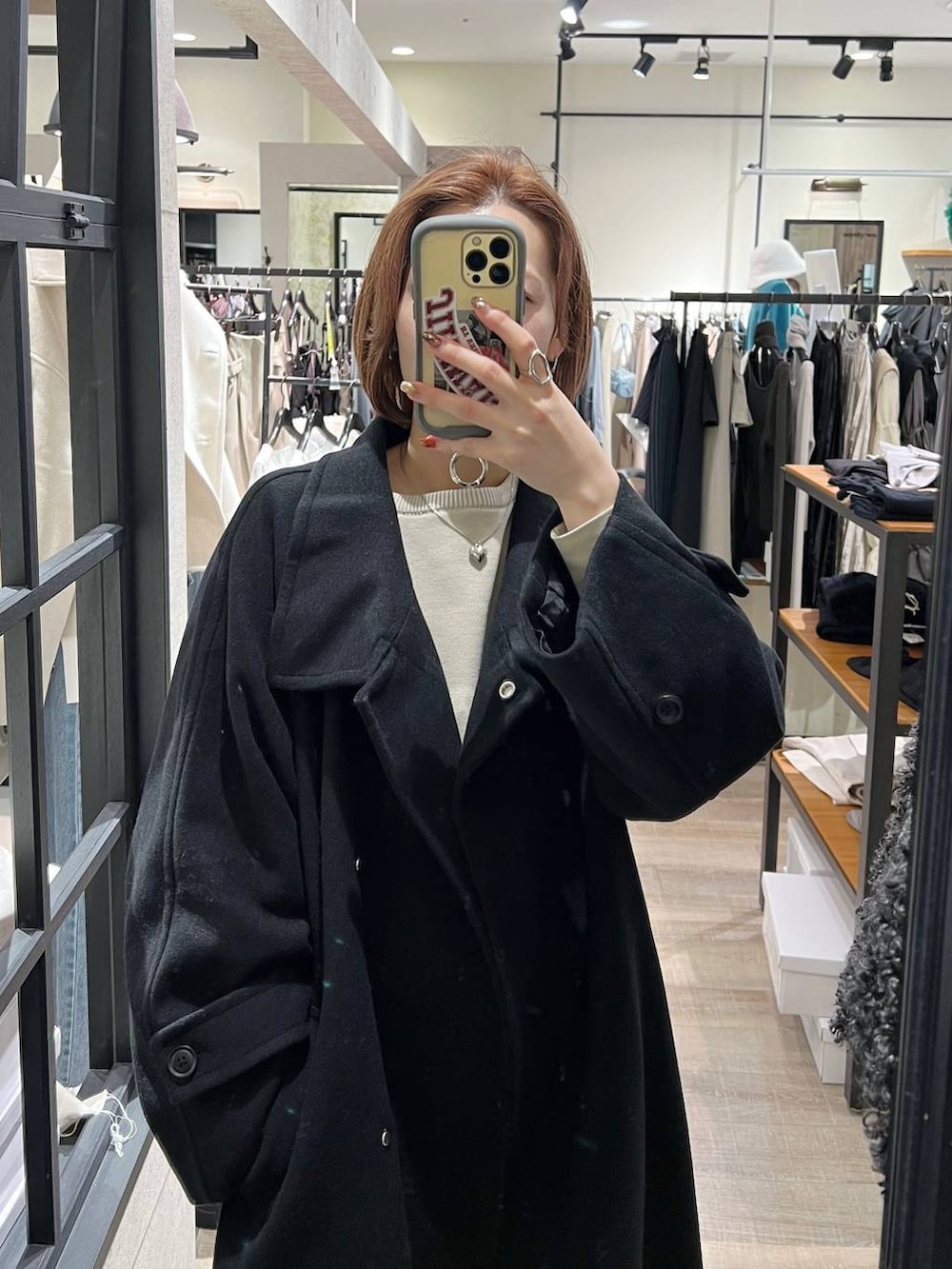 ブラック系のチェスターコート、グレー系のその他パンツ、ホワイト系のニット/セーターを着用したレディースの秋コーディネートの5枚目の写真