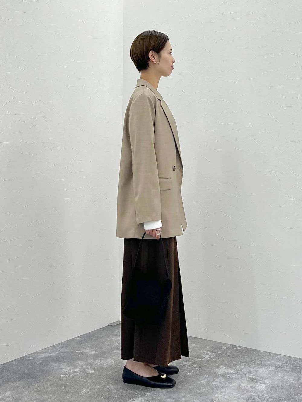 ベージュ系のテーラードジャケット、ホワイト系のTシャツ/カットソー、ブラウン系のスカートを着用したレディースの秋コーディネートの3枚目の写真