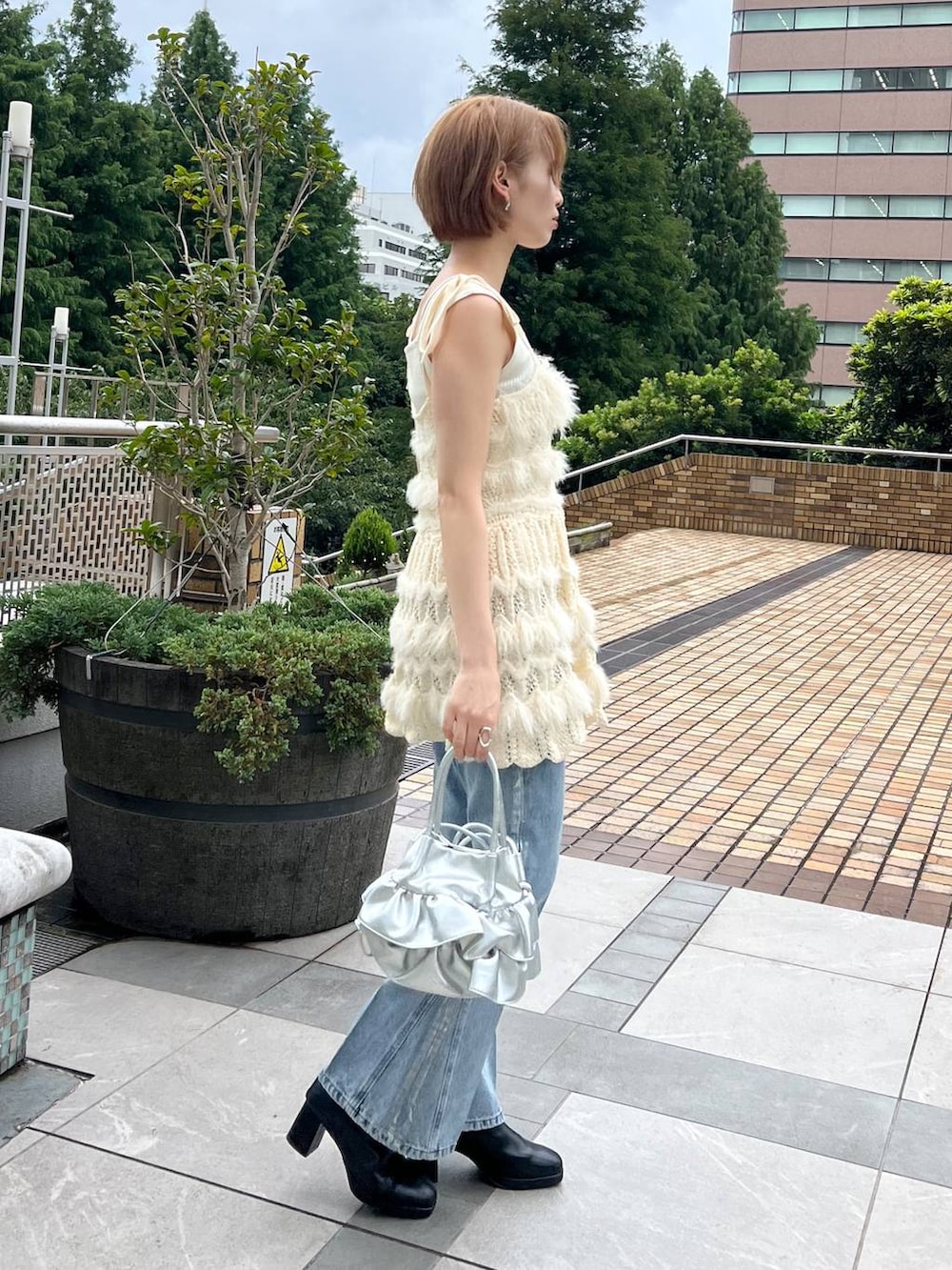 ブルー系のデニムパンツ、ホワイト系のキャミソール、ホワイト系のニット/セーターを着用したレディースの秋コーディネートの2枚目の写真