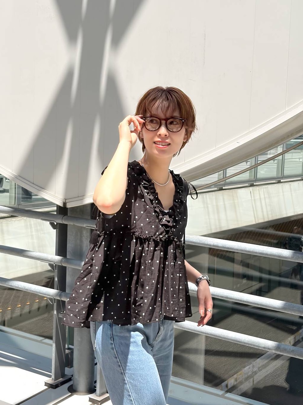 ブラック系のシャツ/ブラウス、ブラック系のハンドバッグ、ブルー系のデニムパンツを着用したレディースの夏コーディネートの6枚目の写真