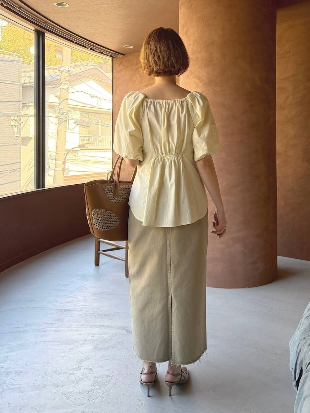 ブラウン系のトートバッグ、ブラウン系のサンダル、ホワイト系のシャツ/ブラウスを着用したレディースの春コーディネートの3枚目の写真