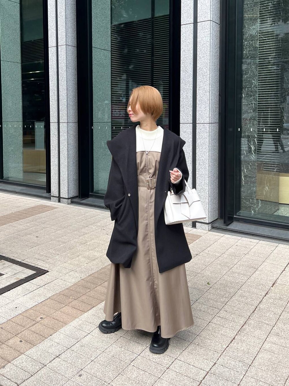 ブラック系のノーカラーコート、ブラック系のブーツ、ホワイト系のショルダーバッグを着用したレディースの冬コーディネートの9枚目の写真