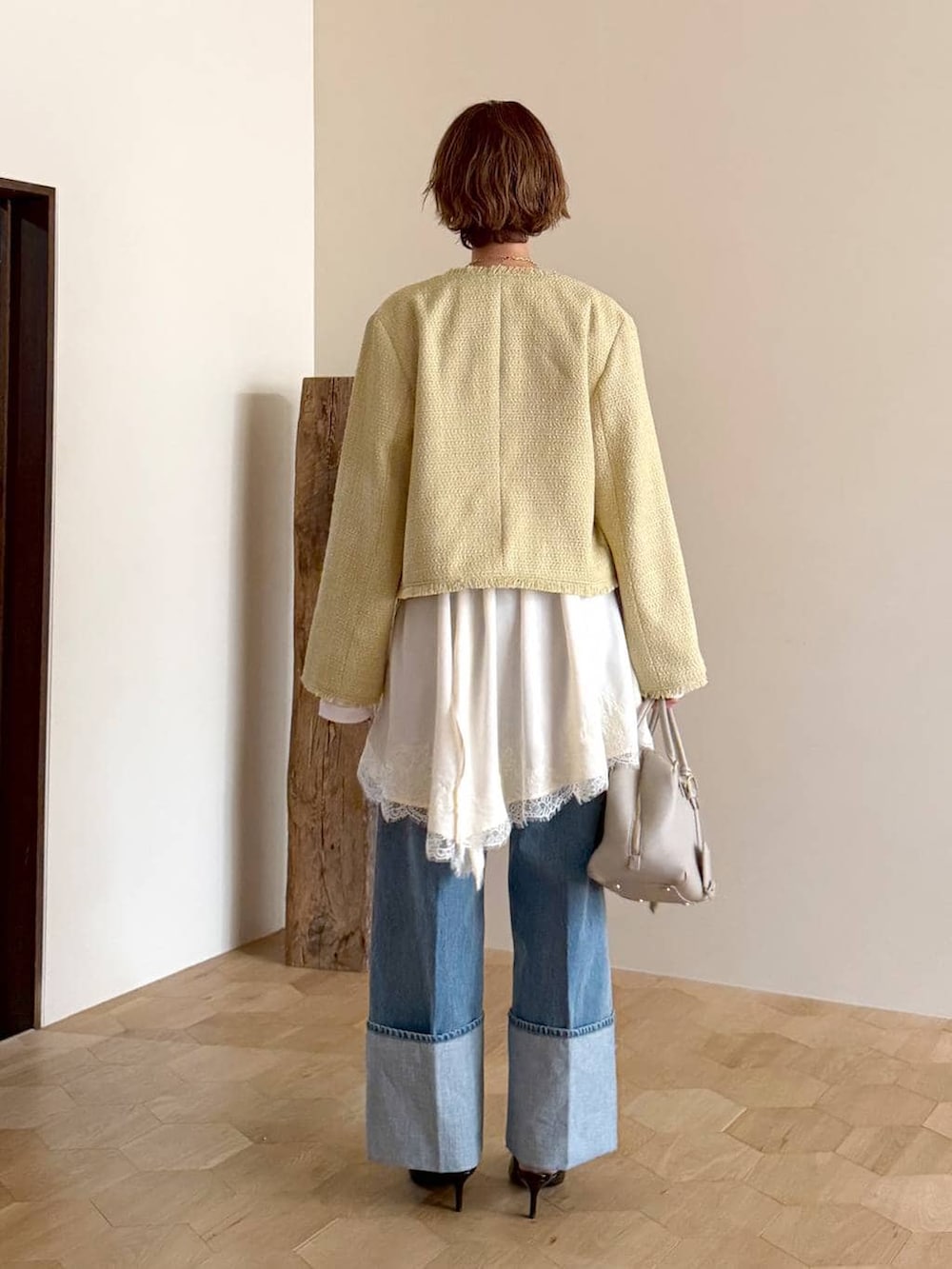 ベージュ系のハンドバッグ、ホワイト系のキャミソール、イエロー系のノーカラージャケットを着用したレディースの冬コーディネートの3枚目の写真