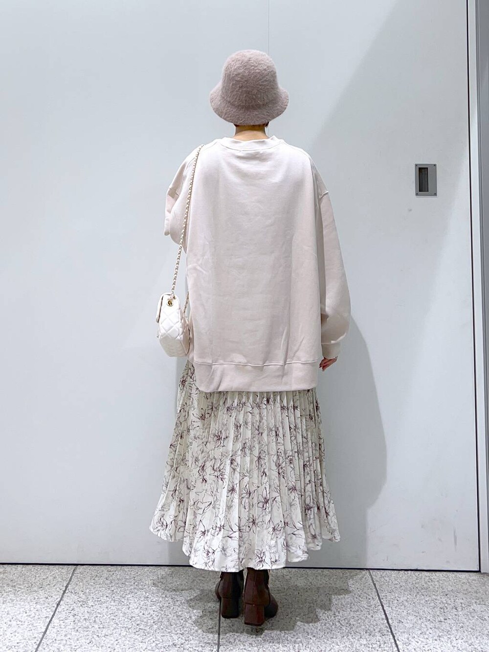 ホワイト系のショルダーバッグ、ブラウン系のブーツ、ベージュ系のスカートを着用したレディースの冬コーディネートの3枚目の写真