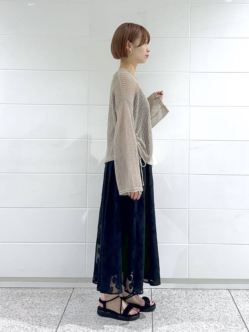 ブラック系のサンダル、ベージュ系のニット/セーター、ブラック系のキャミソールを着用したレディースの春コーディネートの2枚目の写真