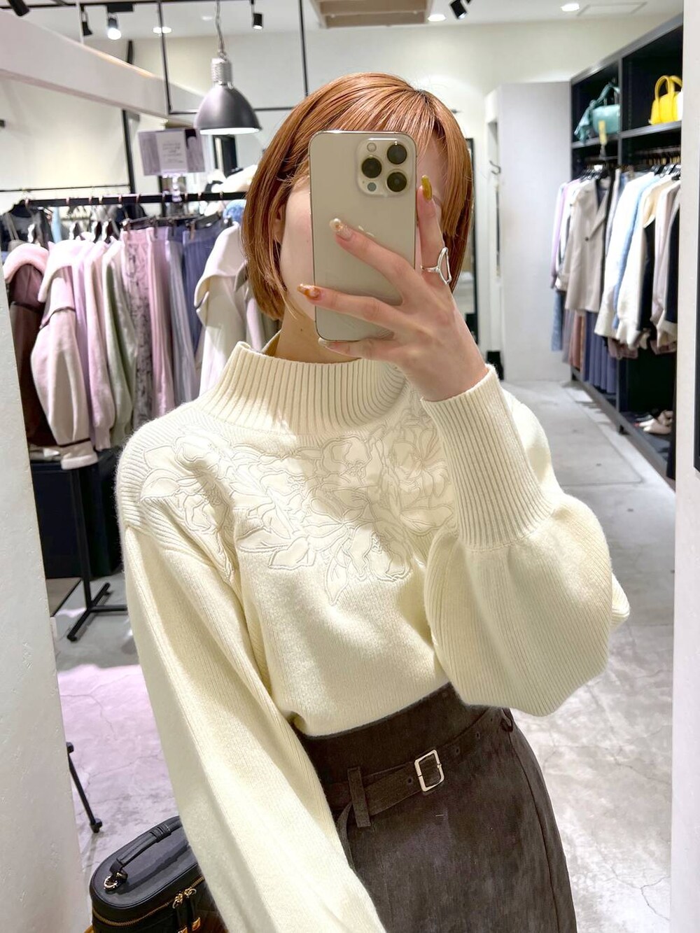 ブラウン系のスカート、ブラック系のブーツ、ブラック系のショルダーバッグを着用したレディースの冬コーディネートの7枚目の写真