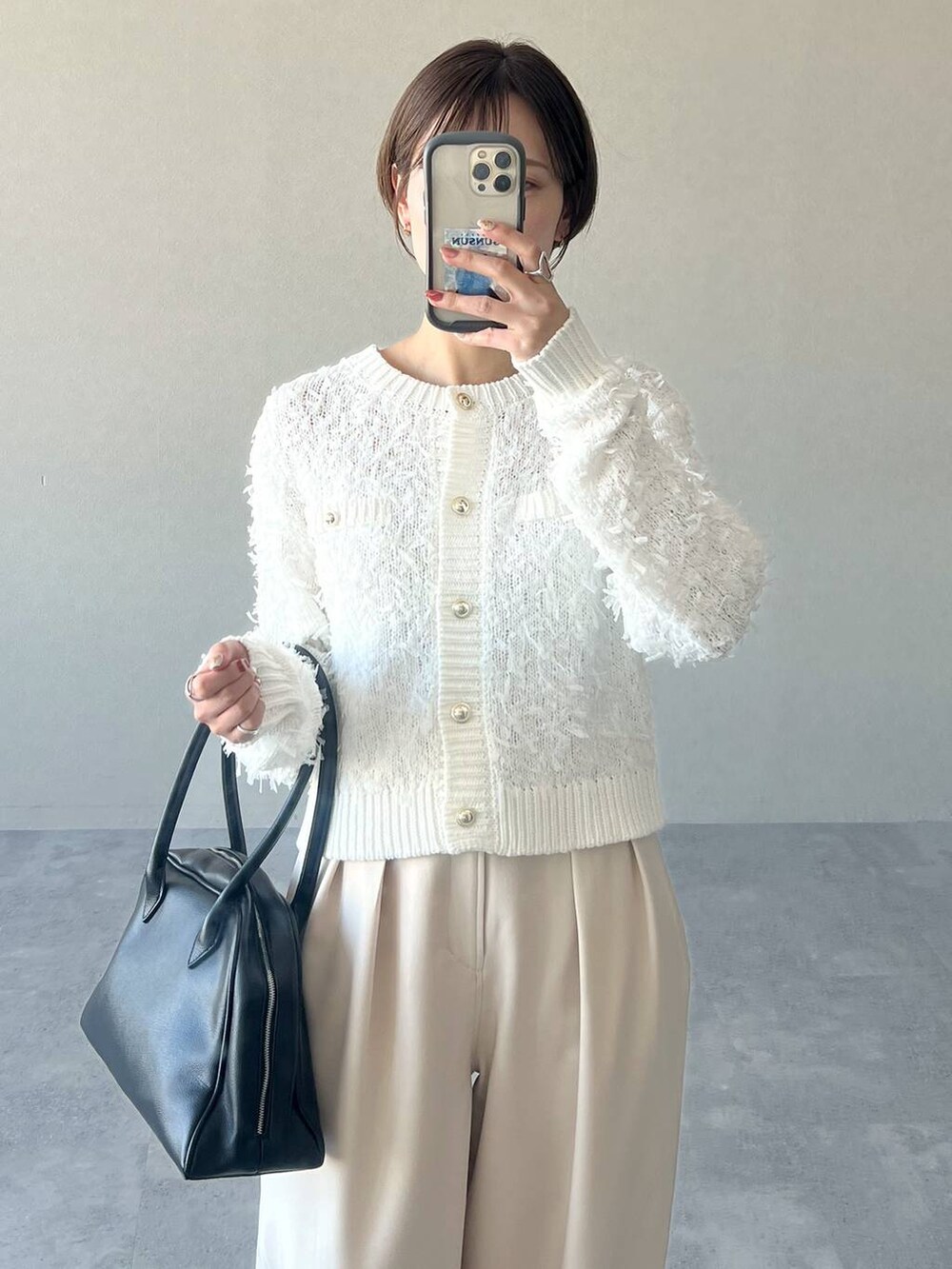 ブラック系のトートバッグ、ホワイト系のカーディガン/ボレロ、ブラック系のパンプスを着用したレディースの冬コーディネートの7枚目の写真