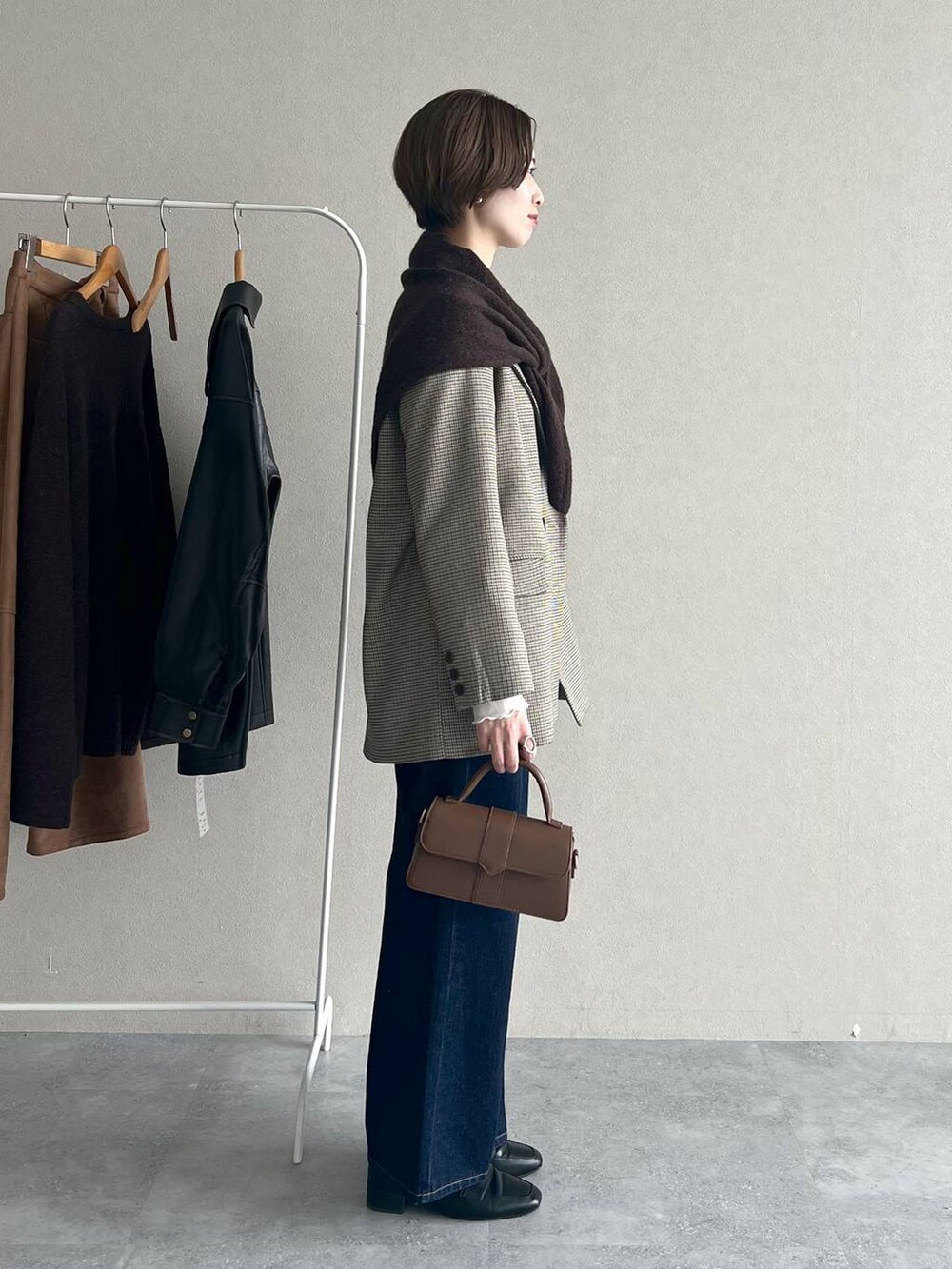 ベージュ系のテーラードジャケット、ブルー系のデニムパンツ、ブラック系のローファーを着用したレディースの秋コーディネートの2枚目の写真