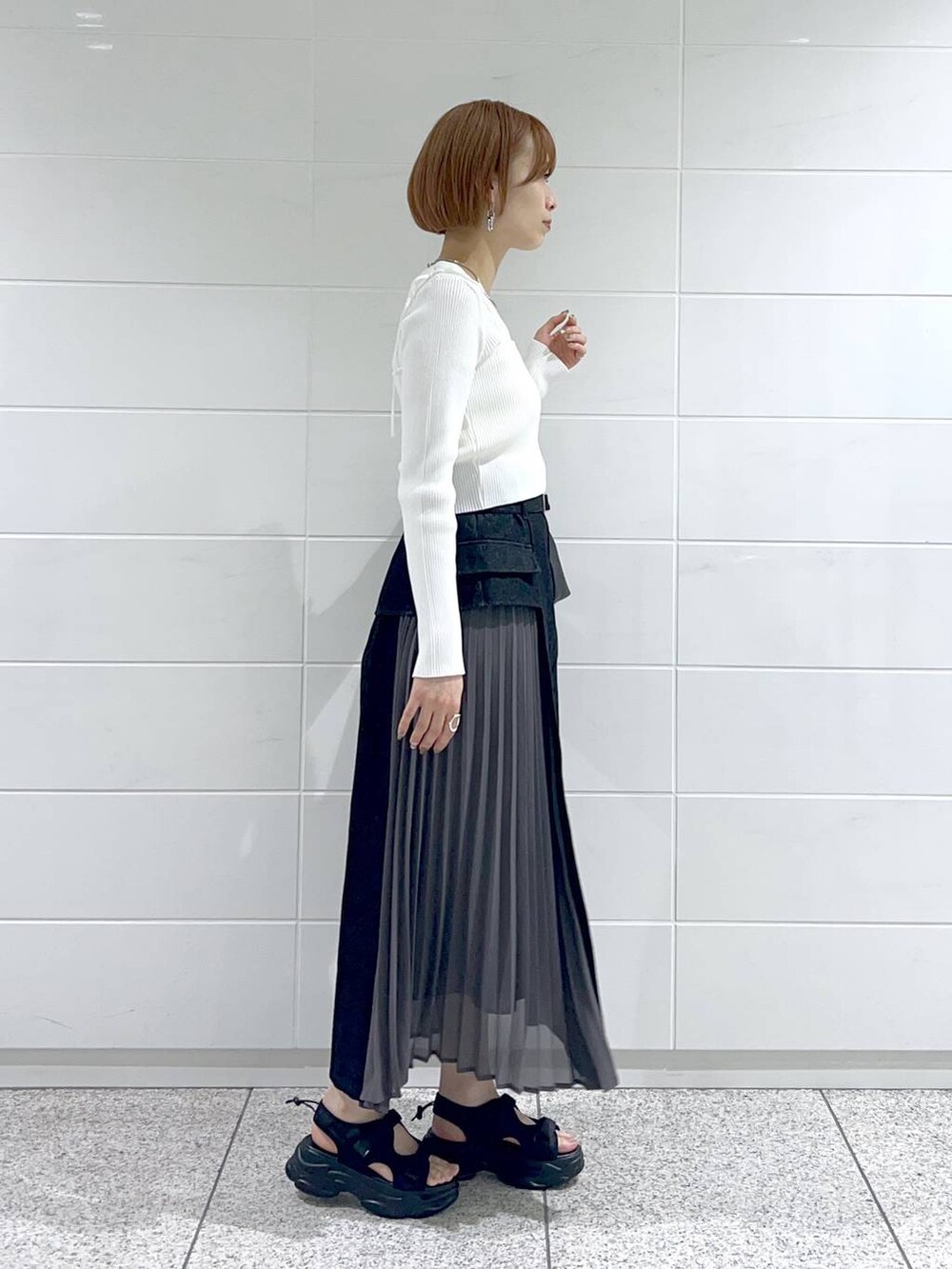 ブラック系のスカート、ホワイト系のカーディガン/ボレロ、ブラック系のサンダルを着用したレディースの春コーディネートの3枚目の写真