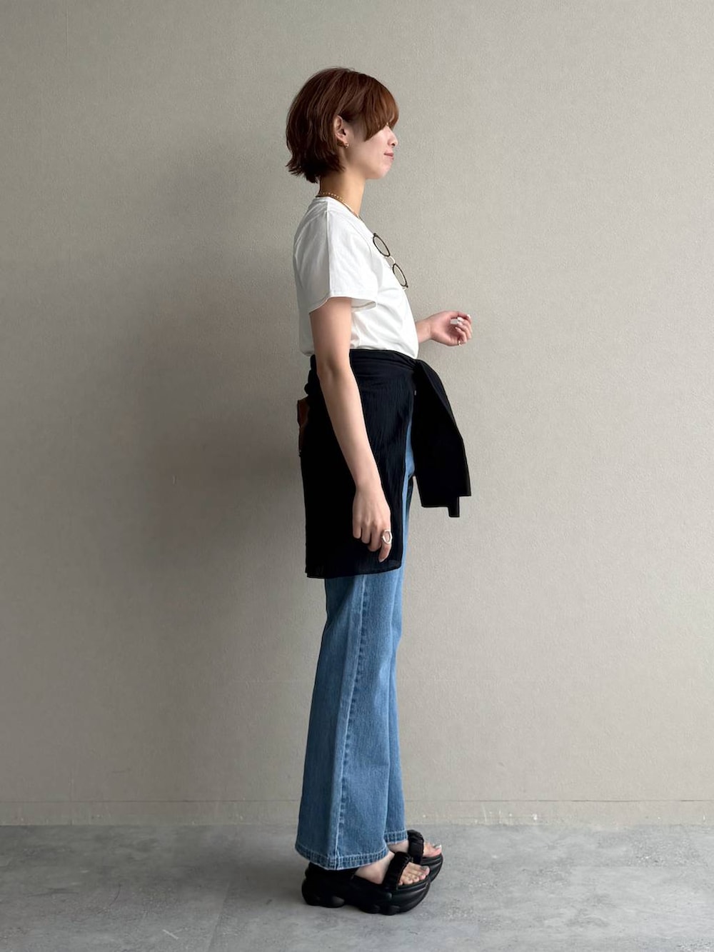 ブラウン系のボストンバッグ、ブルー系のデニムパンツ、ブラック系のシャツ/ブラウスを着用したレディースの夏コーディネートの2枚目の写真
