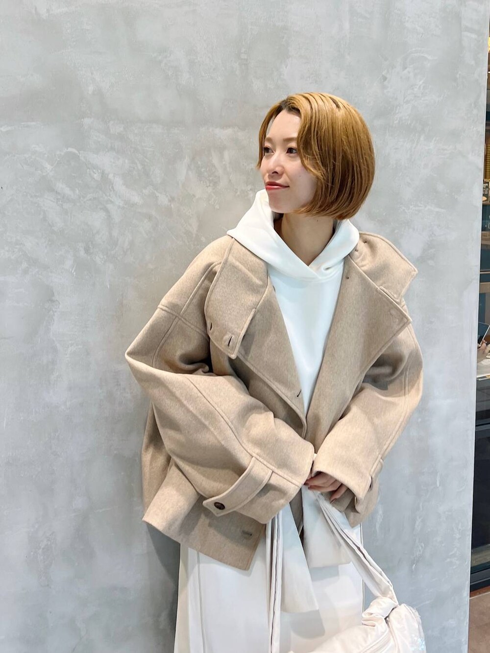 ベージュ系のピーコート、ホワイト系のショルダーバッグ、ブラウン系のブーツを着用したレディースの秋コーディネートの4枚目の写真