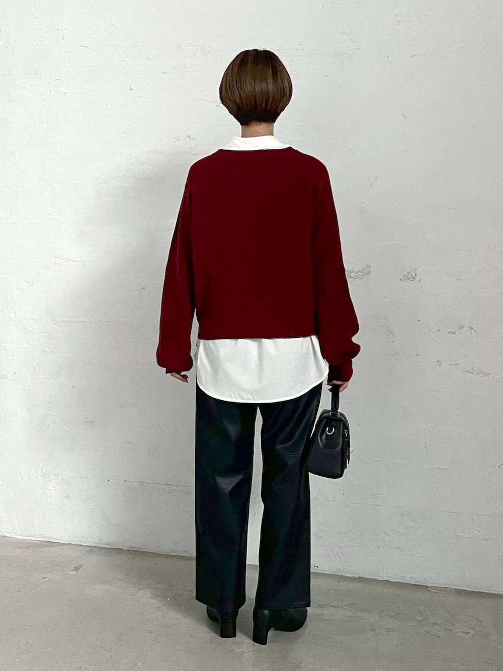 レッド系のニット/セーター、ブラック系のブーツ、ブラック系のスラックスを着用したレディースの冬コーディネートの3枚目の写真