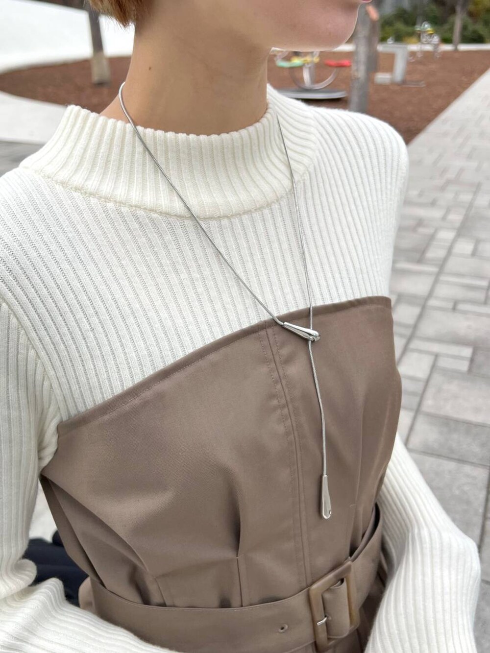 ブラック系のノーカラーコート、ブラック系のブーツ、ホワイト系のショルダーバッグを着用したレディースの冬コーディネートの8枚目の写真