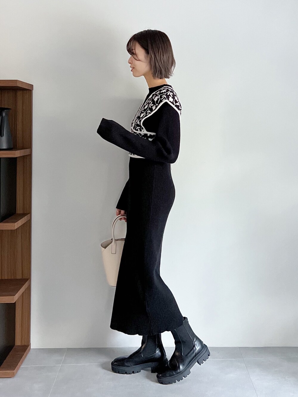 ブラック系のワンピース、ホワイト系のバッグ、ブラック系のブーツを着用したレディースの秋コーディネートの2枚目の写真