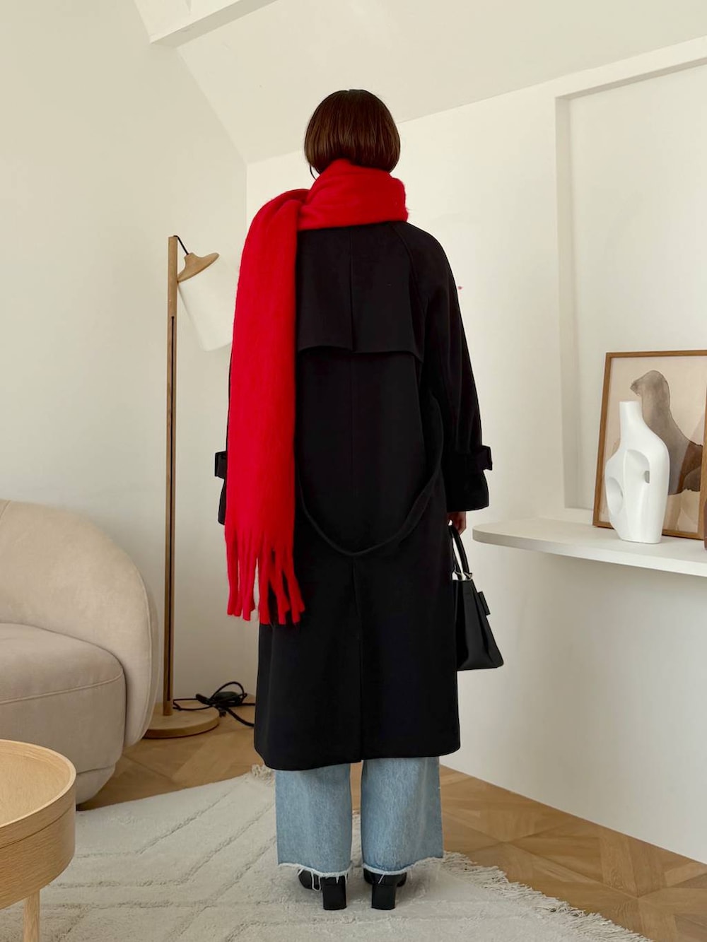 ブルー系のデニムパンツ、ブラック系のショルダーバッグ、ブラック系のチェスターコートを着用したレディースの秋コーディネートの3枚目の写真