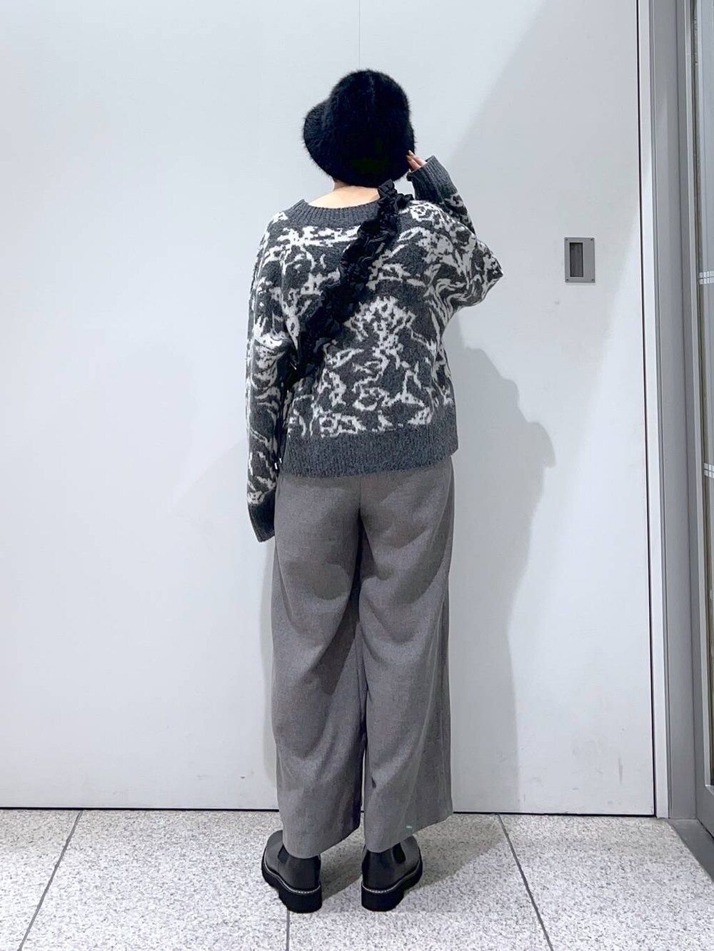 ブラック系のハンドバッグ、ブラック系のブーツ、グレー系のニット/セーターを着用したレディースの冬コーディネートの3枚目の写真