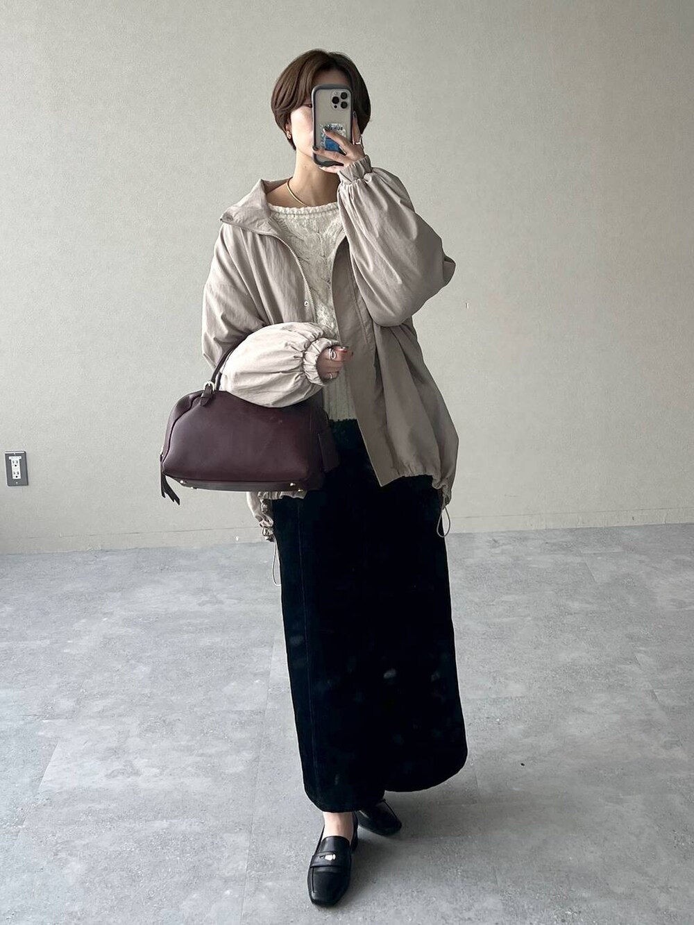 レッド系のハンドバッグ、ブラック系のスカート、ブラック系のローファーを着用したレディースの秋コーディネートの7枚目の写真