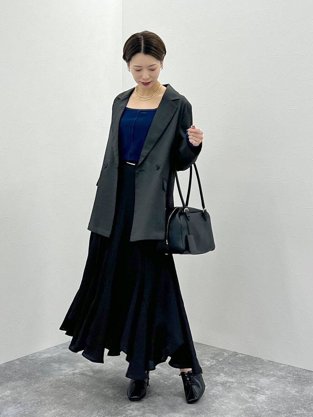 グレー系のテーラードジャケット、ブラック系のハンドバッグ、ブラック系のスカートを着用したレディースの秋コーディネートの4枚目の写真