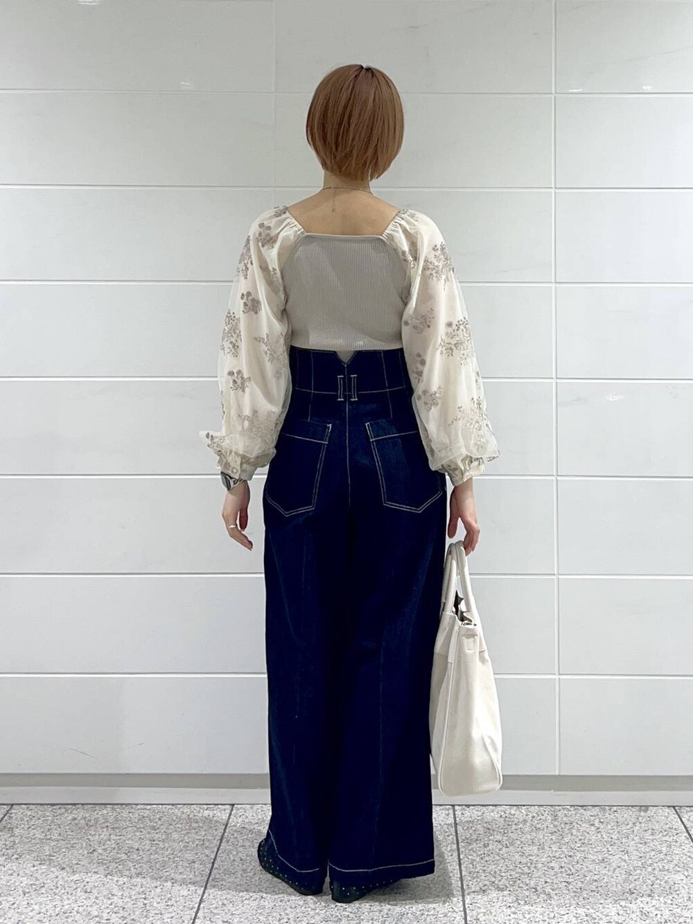 ホワイト系のトートバッグ、ブラック系のバレエシューズ、ブルー系のデニムパンツを着用したレディースの春コーディネートの3枚目の写真