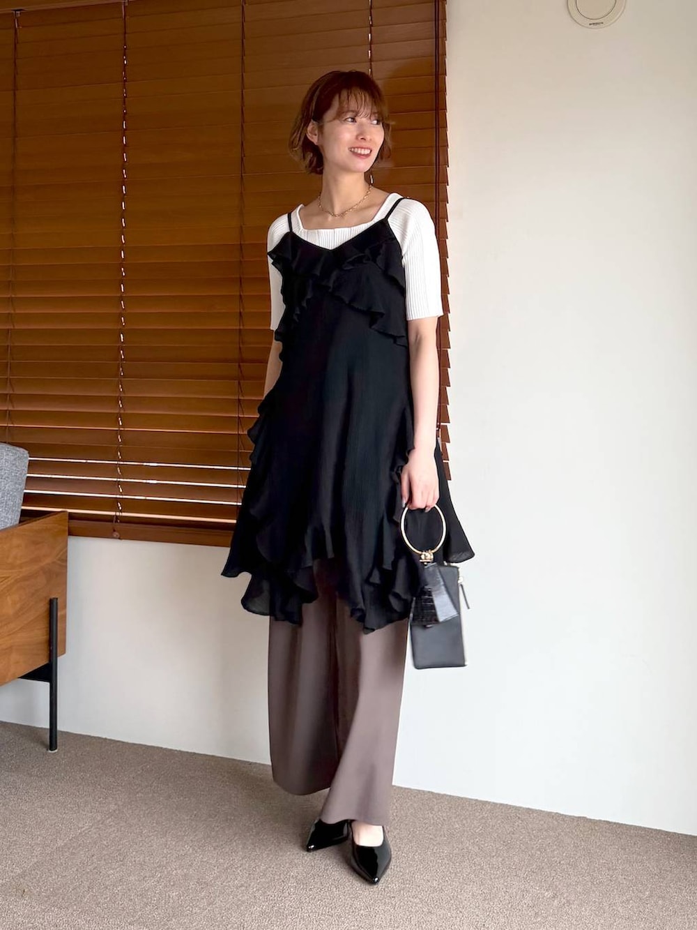 ブラック系のサンダル、ブラック系のショルダーバッグ、ブラック系のチュニックを着用したレディースの春コーディネートの5枚目の写真