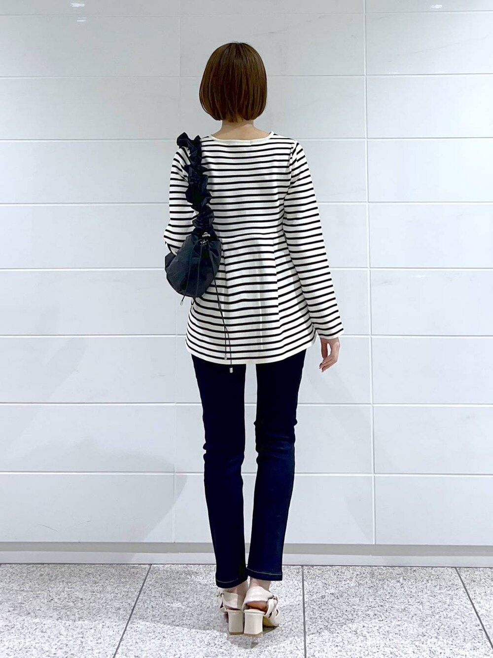 ホワイト系のカーディガン/ボレロ、ブルー系のデニムパンツ、ブラック系のハンドバッグを着用したレディースの春コーディネートの3枚目の写真