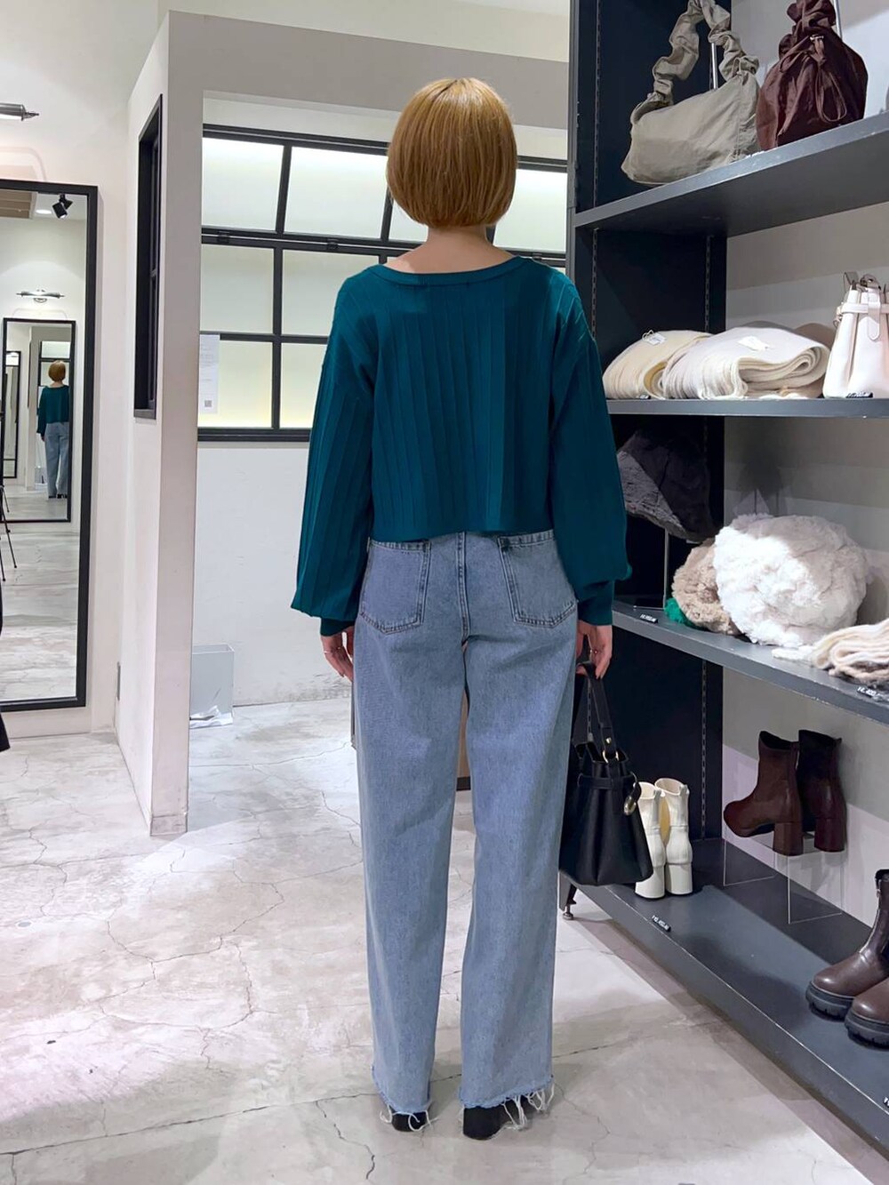 ブルー系のデニムパンツ、ブラック系のショルダーバッグ、ブラック系のブーツを着用したレディースの秋コーディネートの3枚目の写真