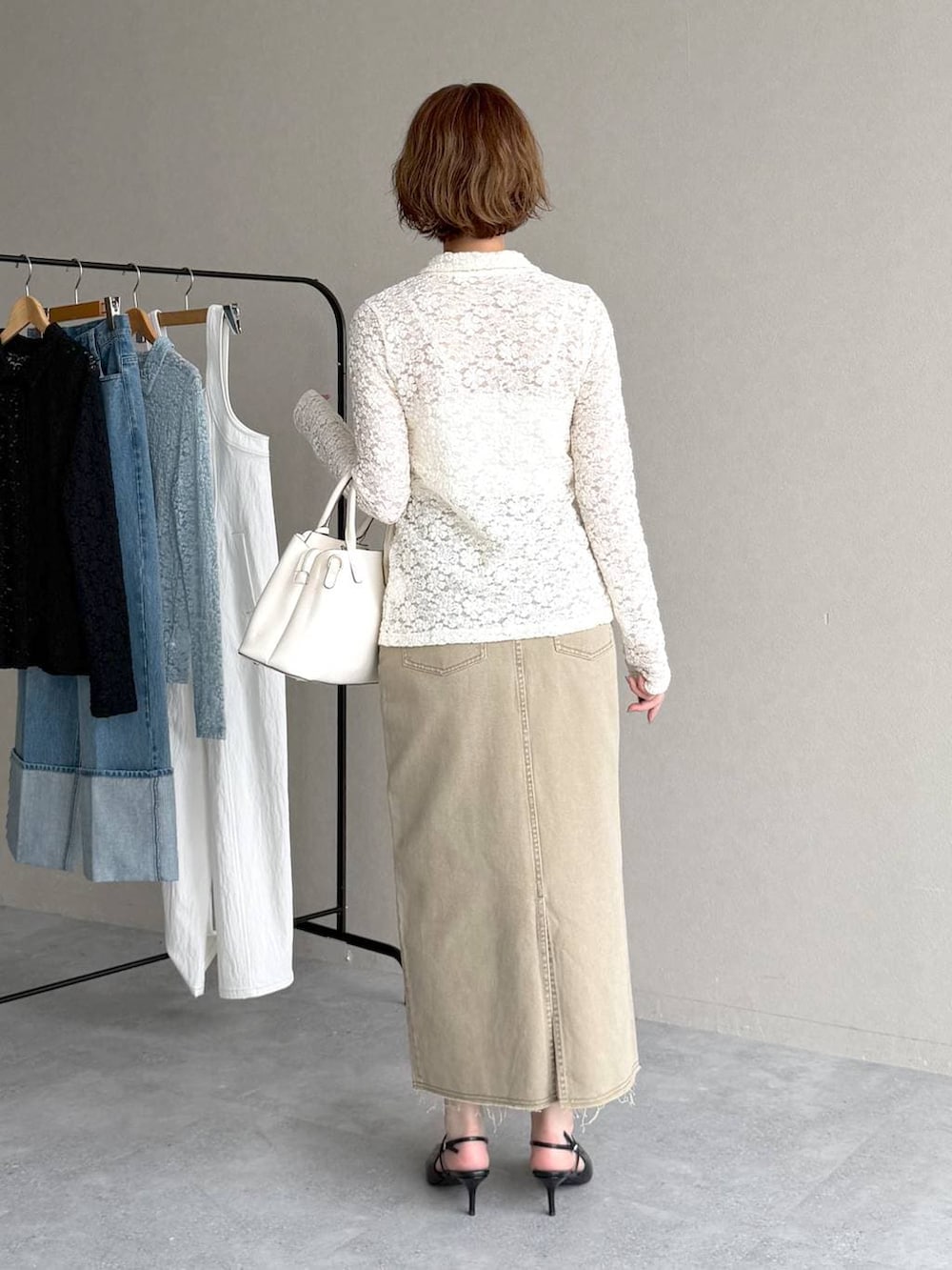 ブラック系のサンダル、ブルー系のテーラードジャケット、ベージュ系のスカートを着用したレディースの春コーディネートの6枚目の写真