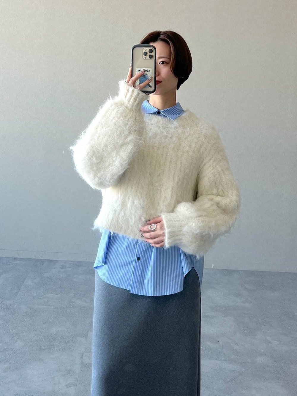 グレー系のスカート、ブラック系のブーツ、ホワイト系のニット/セーターを着用したレディースの冬コーディネートの4枚目の写真