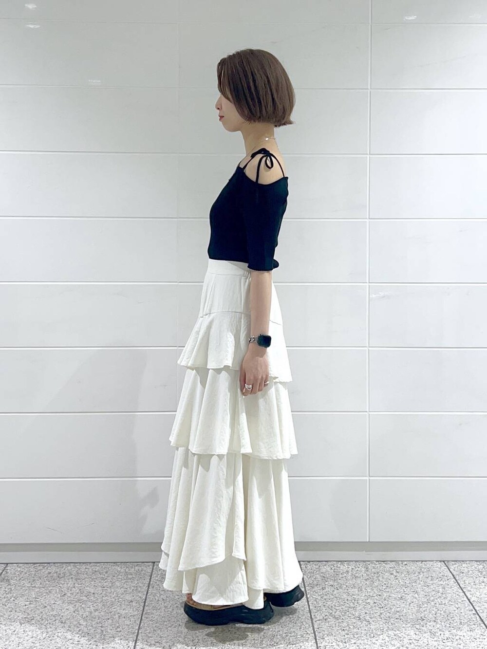 ホワイト系のスカート、ベージュ系のサンダル、ブラック系のニット/セーターを着用したレディースの春コーディネートの2枚目の写真