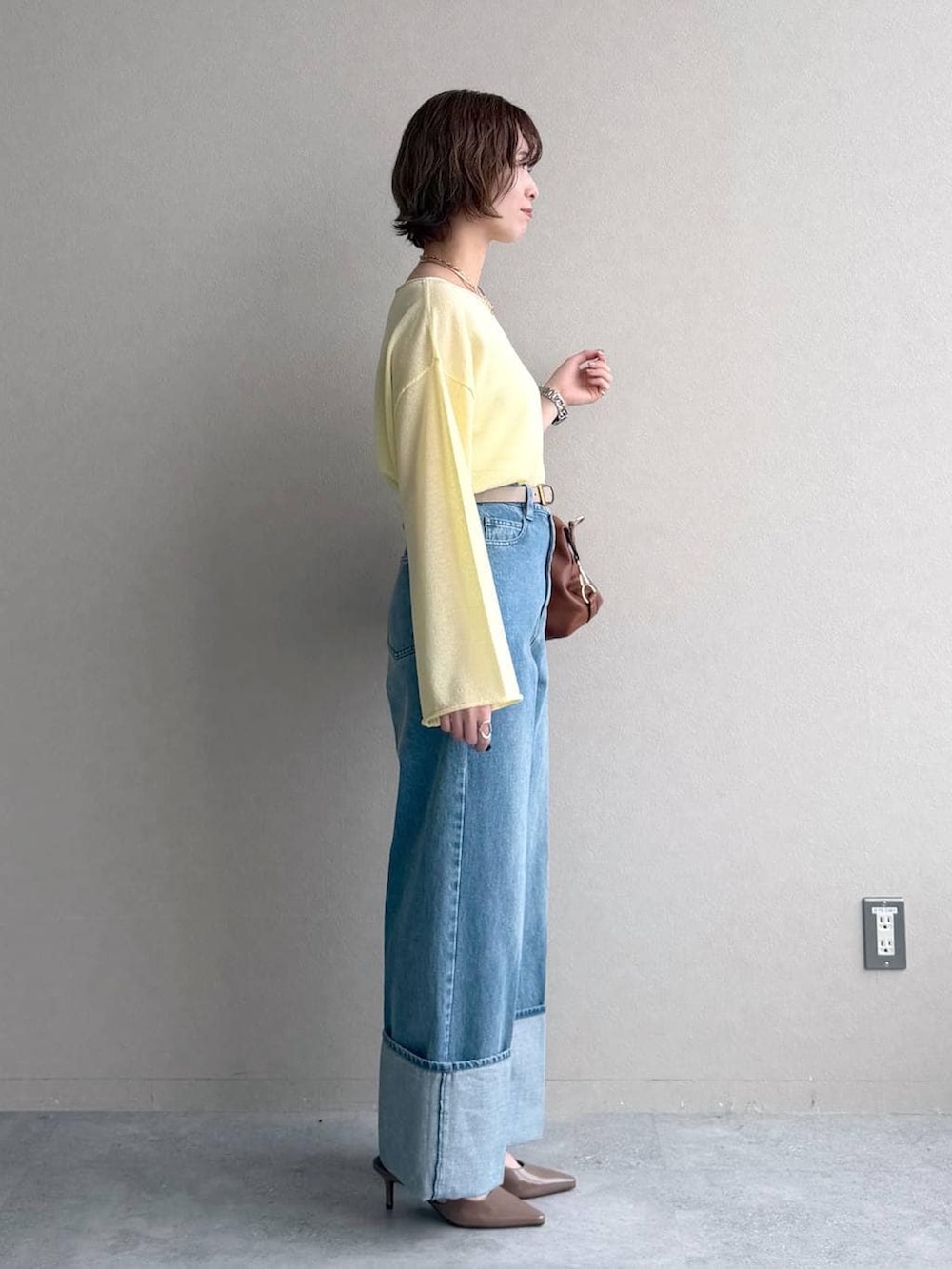 イエロー系のニット/セーター、ブラウン系のボストンバッグ、ベージュ系のトレンチコートを着用したレディースの冬コーディネートの6枚目の写真