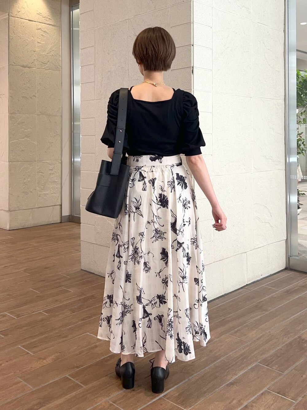 ブラック系のショルダーバッグ、ブラック系のTシャツ/カットソー、ホワイト系のスカートを着用したレディースの夏コーディネートの3枚目の写真