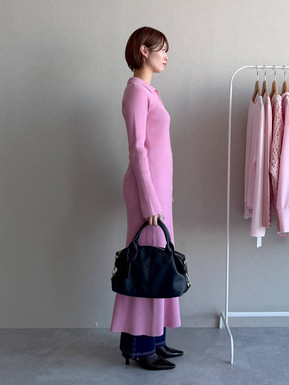 ブラック系のボストンバッグ、ピンク系のワンピース、ブルー系のデニムパンツを着用したレディースの冬コーディネートの2枚目の写真