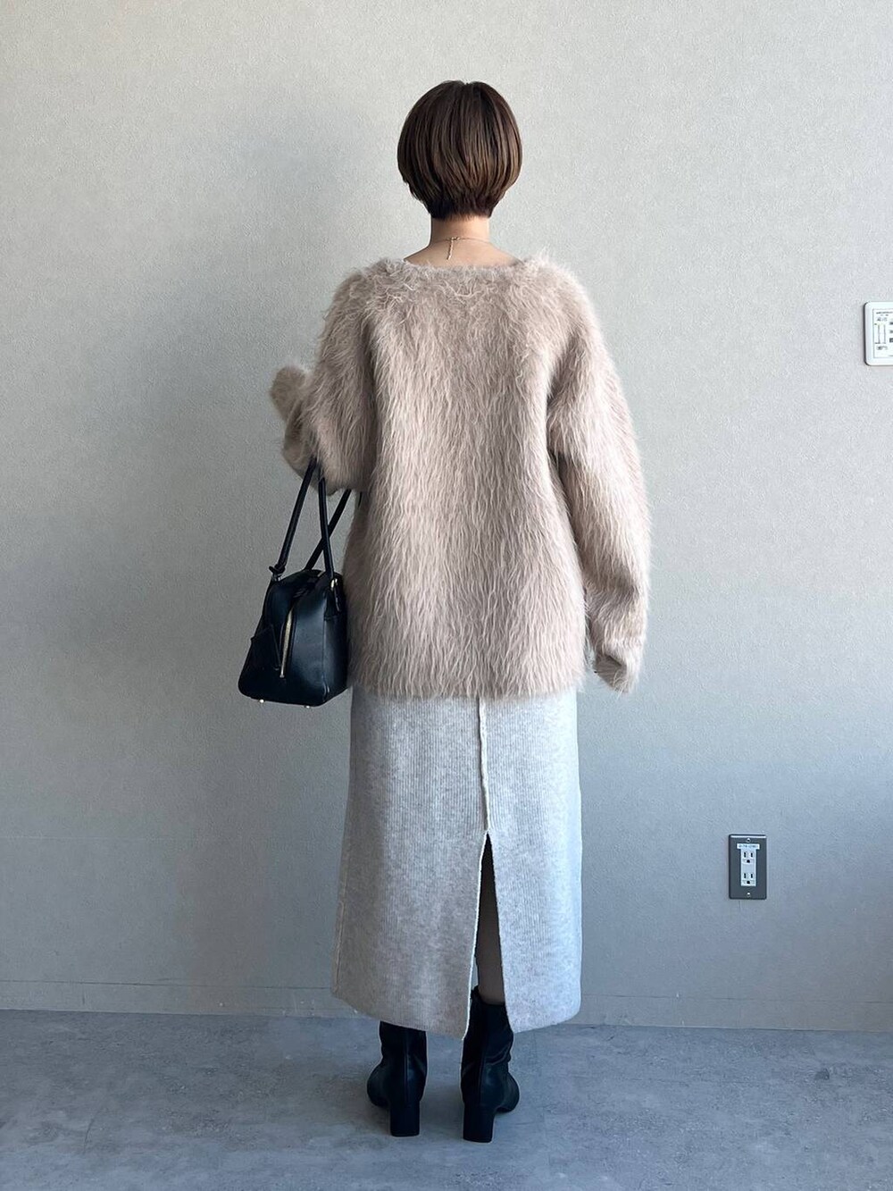 ブラック系のハンドバッグ、ブラック系のブーツ、ベージュ系のカーディガン/ボレロを着用したレディースの冬コーディネートの3枚目の写真