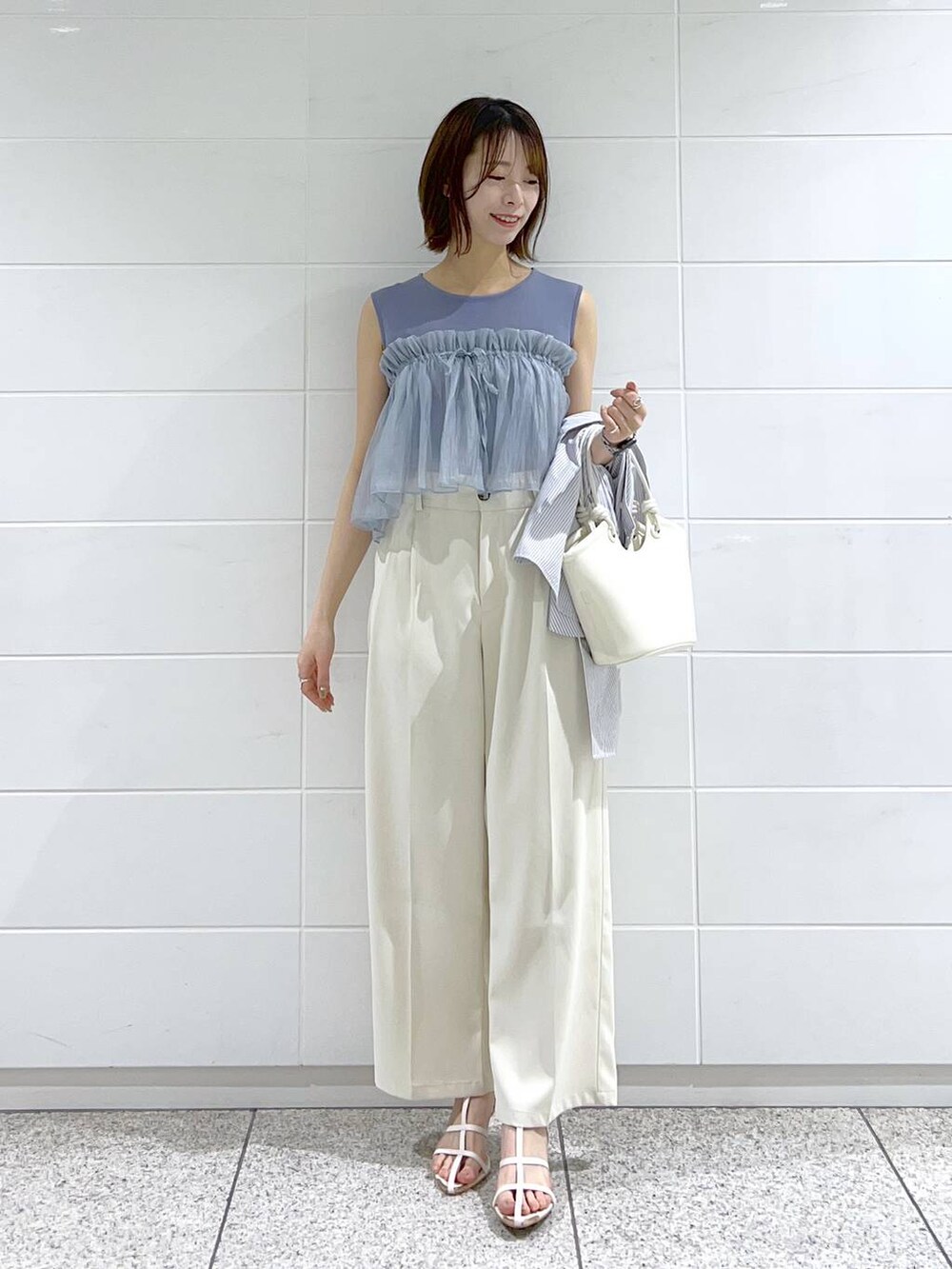 ブルー系のシャツ/ブラウス、ホワイト系のサンダル、ホワイト系のハンドバッグを着用したレディースの春コーディネートの4枚目の写真