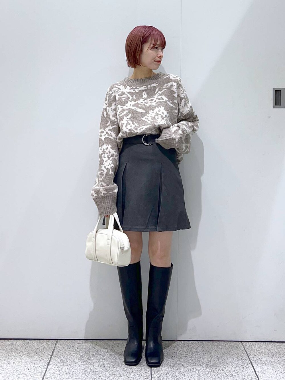 ブラック系のブルゾン、ホワイト系のボストンバッグ、ブラック系のブーツを着用したレディースの秋コーディネートの4枚目の写真