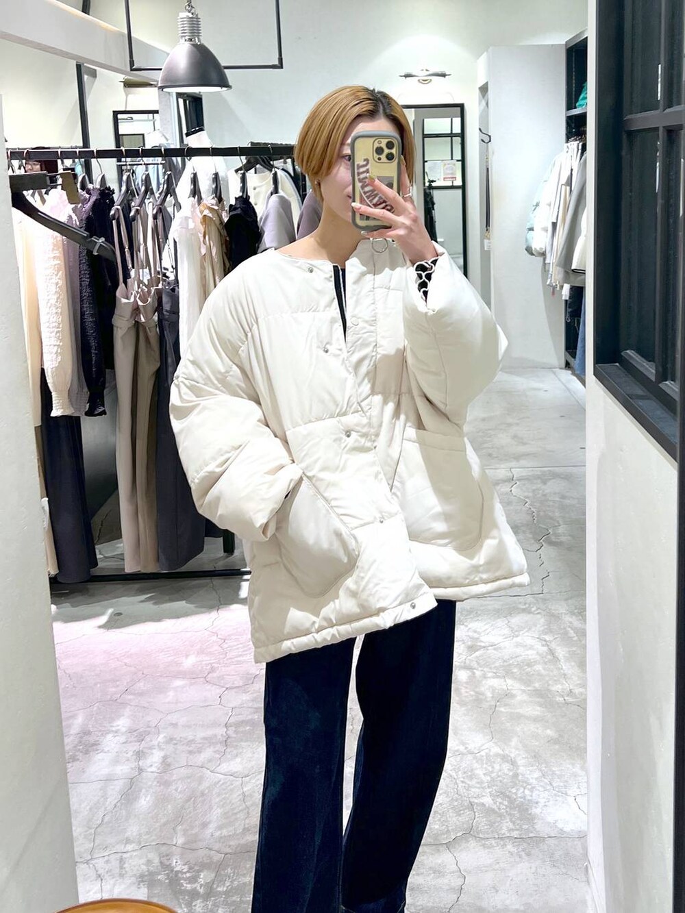 ホワイト系のブルゾン、ホワイト系のショルダーバッグ、ブルー系のスラックスを着用したレディースの冬コーディネートの7枚目の写真