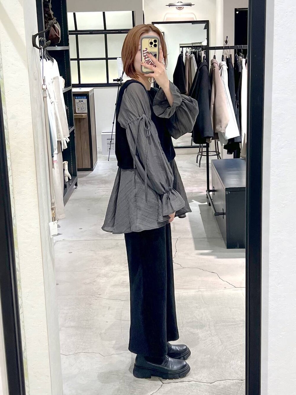 シルバー系のショルダーバッグ、ブラック系のブーツ、ブラック系のスカートを着用したレディースの秋コーディネートの8枚目の写真