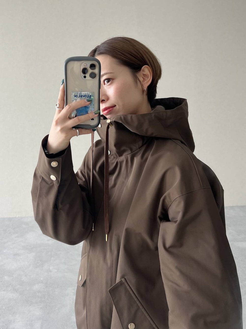 ブラック系のハンドバッグ、ブラウン系のマウンテンパーカー、ブラック系のスリッポンを着用したレディースの秋コーディネートの5枚目の写真