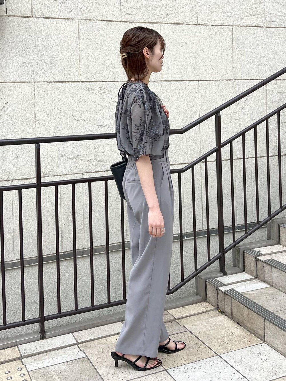 ブラック系のシャツ/ブラウス、ブラック系のサンダル、ブラック系のハンドバッグを着用したレディースの春コーディネートの2枚目の写真